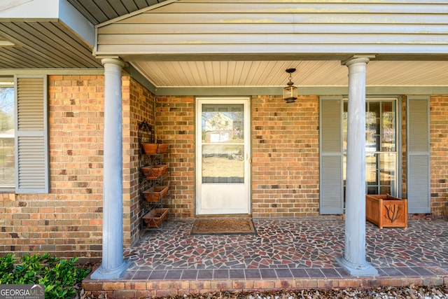 property entrance with covered porch and brick siding