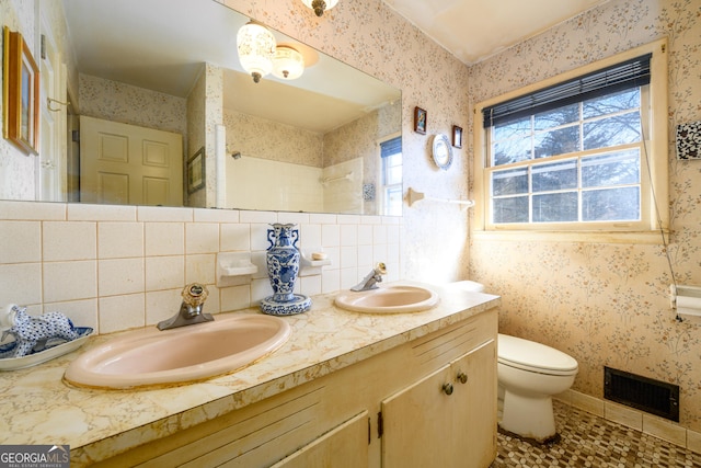 bathroom featuring double vanity, wallpapered walls, visible vents, and a sink