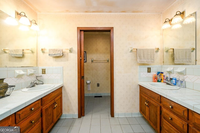 full bath with two vanities, a sink, and wallpapered walls