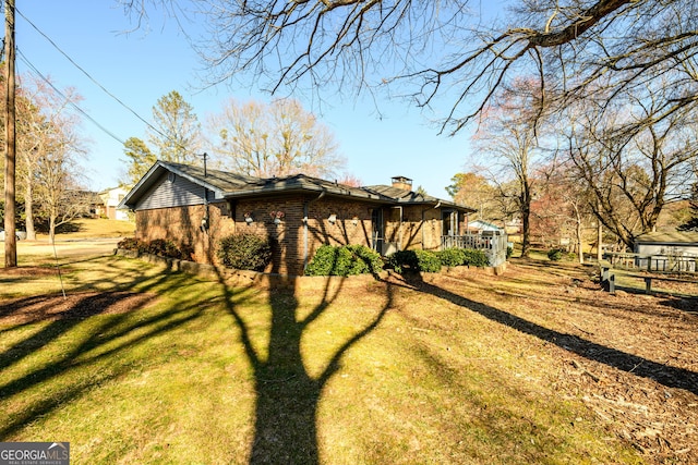 back of property featuring a yard, brick siding, and a chimney