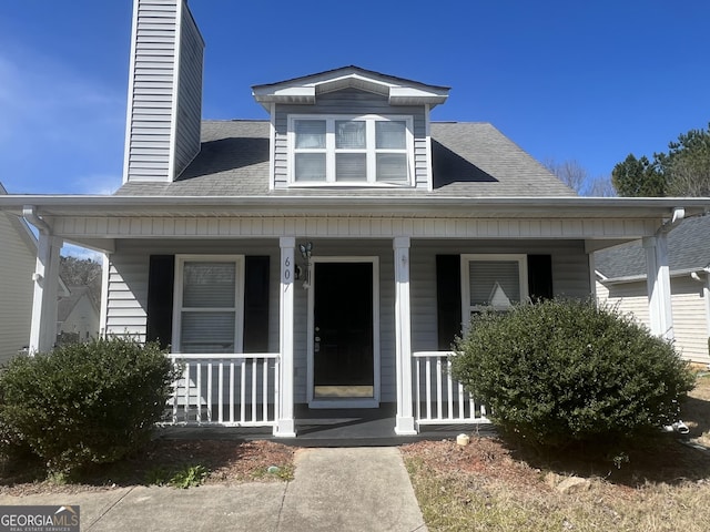 bungalow featuring a porch, a shingled roof, and a chimney