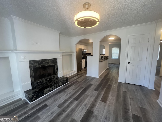 unfurnished living room with a high end fireplace, dark wood-style flooring, crown molding, and a textured ceiling