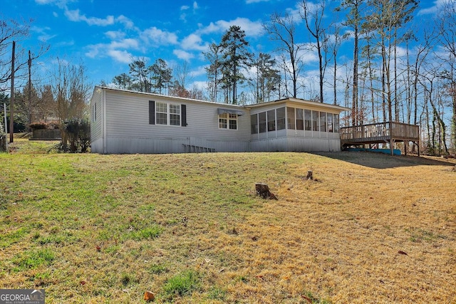 view of front facade with a front yard, a wooden deck, and a sunroom