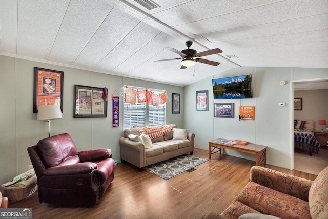 living area with a ceiling fan, visible vents, vaulted ceiling, and wood finished floors