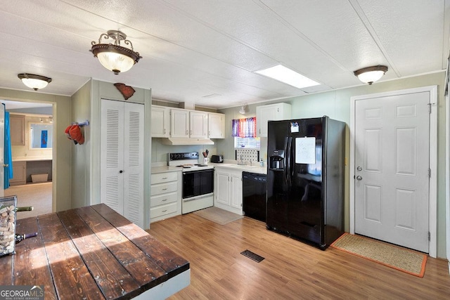 kitchen with black appliances, a sink, visible vents, and white cabinets