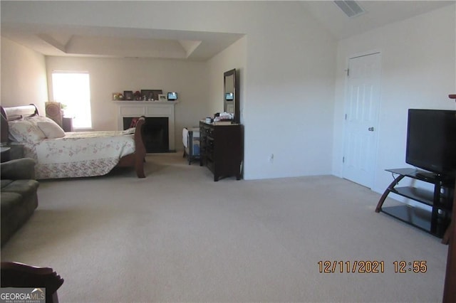 bedroom featuring lofted ceiling, carpet floors, a fireplace, visible vents, and a raised ceiling