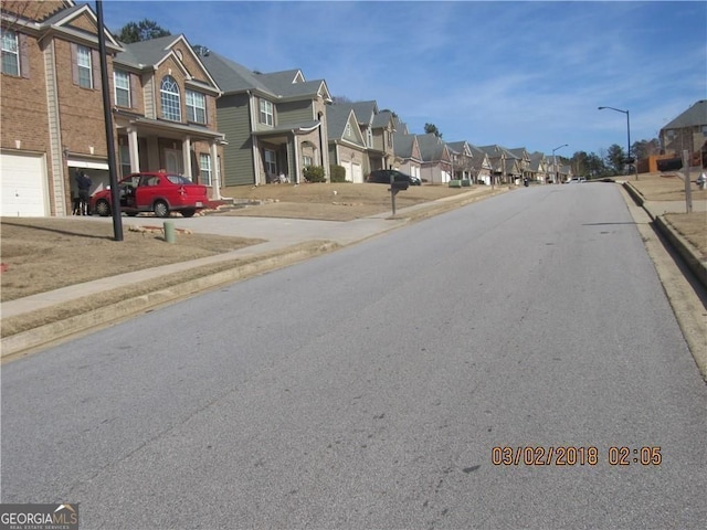 view of street featuring sidewalks, a residential view, curbs, and street lights