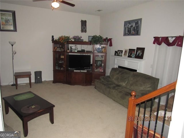 carpeted living area featuring a fireplace and a ceiling fan