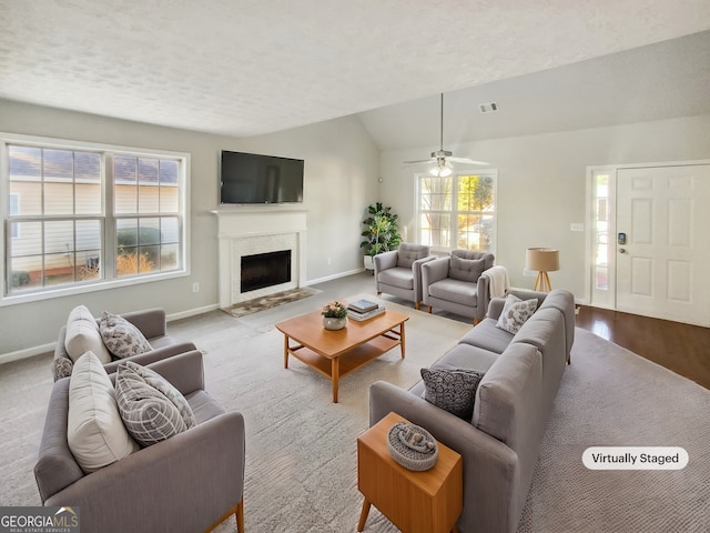 living area featuring a fireplace, visible vents, vaulted ceiling, a textured ceiling, and baseboards