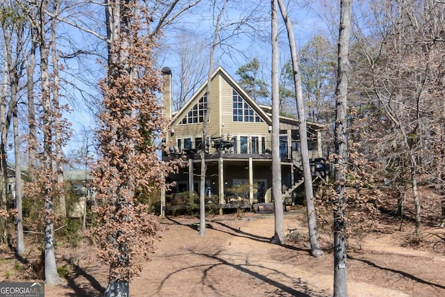 back of property featuring a deck, a chimney, and stairs