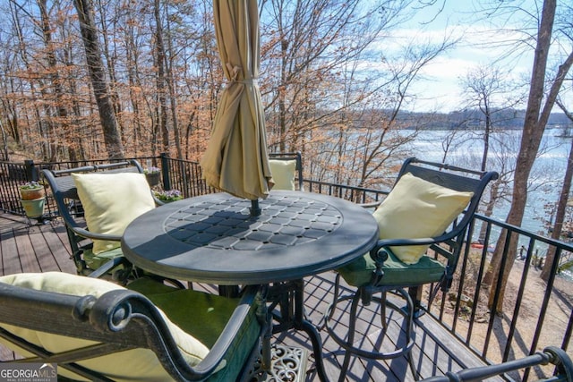 wooden terrace featuring outdoor dining area and a water view