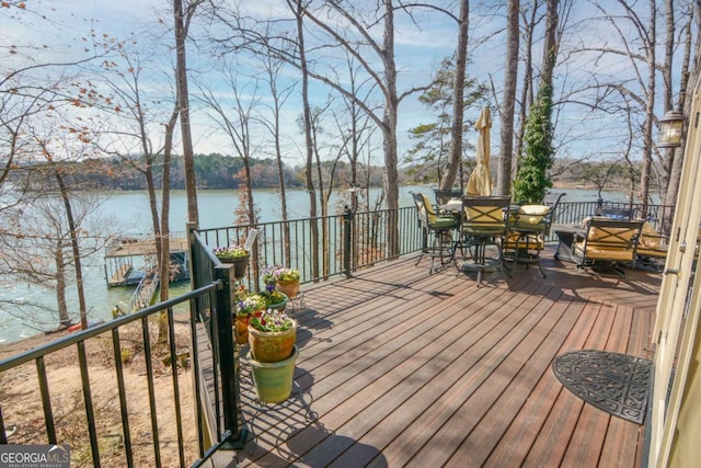 wooden deck with a water view and outdoor dining area