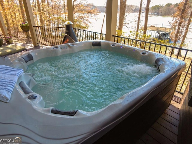 wooden deck with a water view and an outdoor hot tub