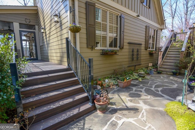 view of exterior entry with board and batten siding and a patio