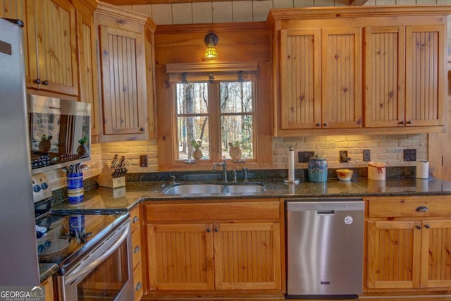 kitchen with stainless steel appliances, backsplash, dark stone countertops, and a sink