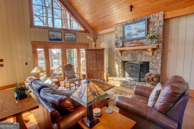 living area with french doors, a stone fireplace, wood finished floors, and wooden walls