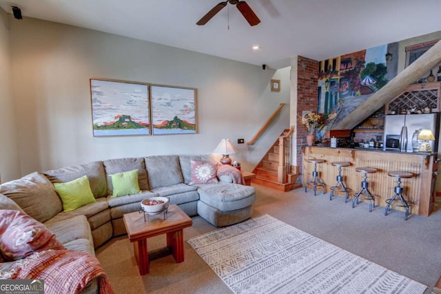 living room with a ceiling fan, carpet, indoor wet bar, and stairs