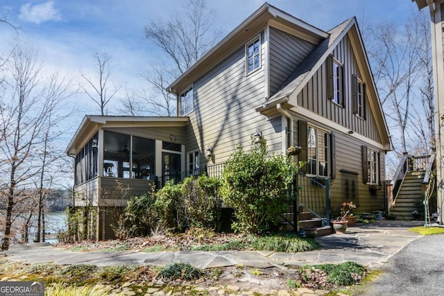 view of front of property with stairway, board and batten siding, and a sunroom