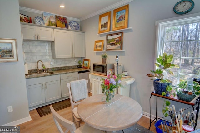 kitchen featuring crown molding, backsplash, light wood-style flooring, appliances with stainless steel finishes, and a sink