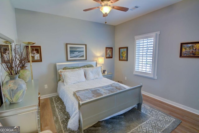 bedroom featuring baseboards, visible vents, ceiling fan, and wood finished floors