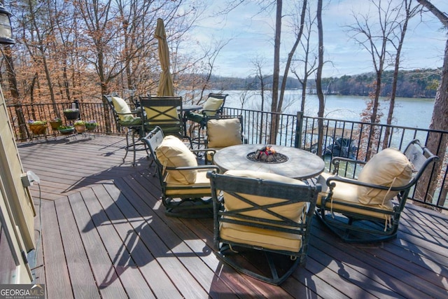 wooden deck featuring a water view and a fire pit