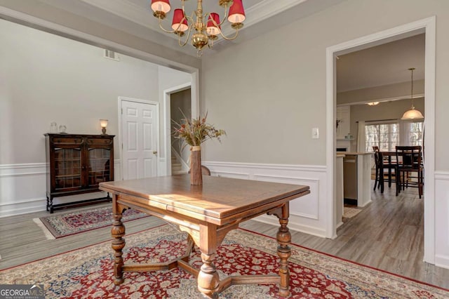 interior space with a decorative wall, a wainscoted wall, visible vents, light wood-style floors, and an inviting chandelier