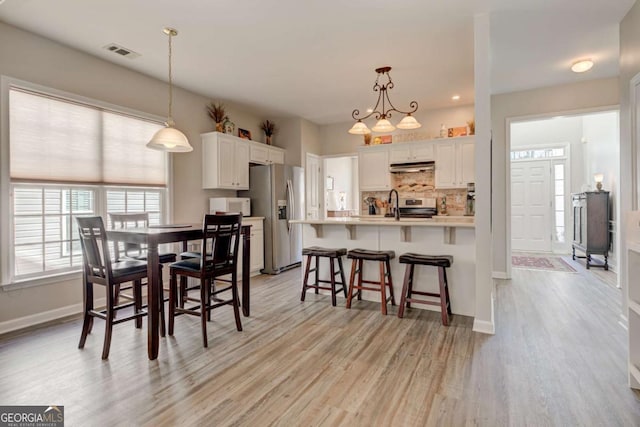 dining area featuring light wood-type flooring, visible vents, and baseboards