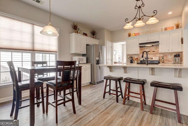 dining area featuring visible vents, light wood-style flooring, and baseboards