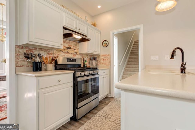 kitchen featuring decorative backsplash, under cabinet range hood, white cabinetry, a sink, and gas stove