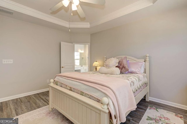 bedroom with a tray ceiling, wood finished floors, visible vents, and crown molding