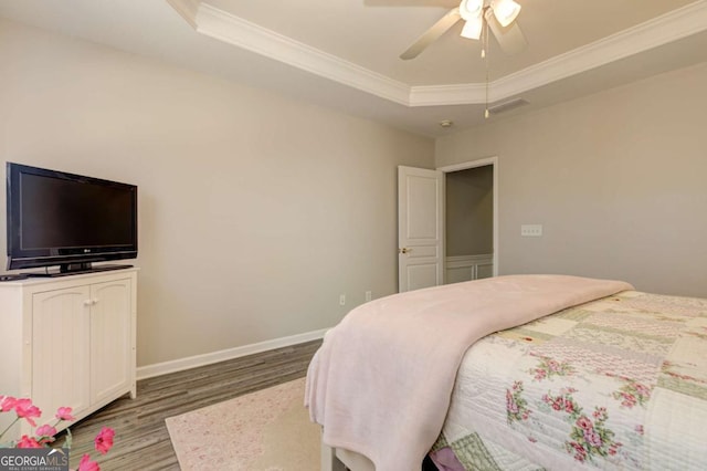 bedroom featuring baseboards, visible vents, a raised ceiling, ornamental molding, and wood finished floors