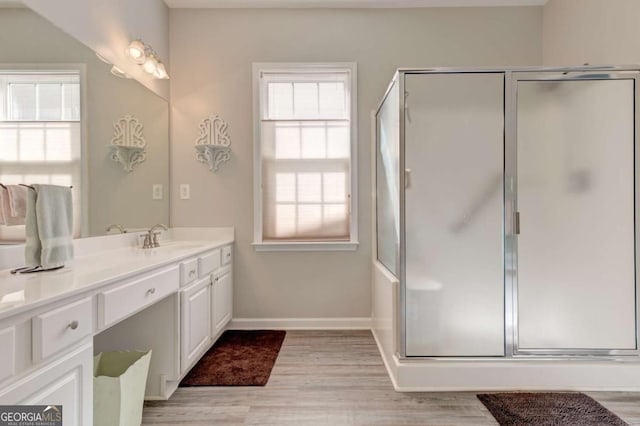 bathroom featuring baseboards, an enclosed shower, wood finished floors, and vanity