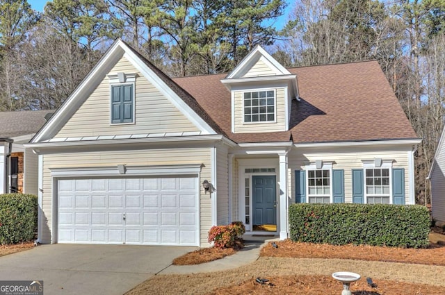 view of front facade featuring roof with shingles, driveway, and an attached garage