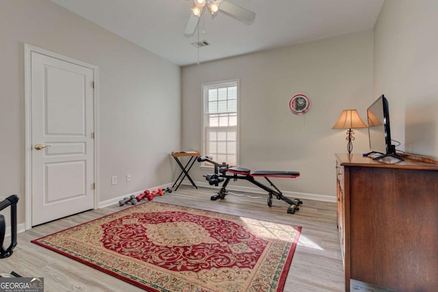 exercise room with a ceiling fan, baseboards, visible vents, and wood finished floors