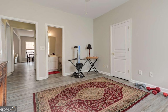 interior space with ensuite bath, baseboards, and wood finished floors