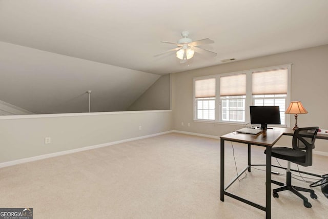 office space with baseboards, visible vents, vaulted ceiling, and light colored carpet