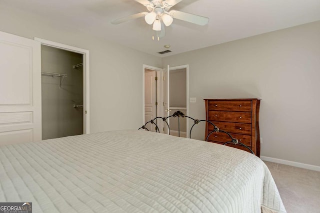 carpeted bedroom featuring a walk in closet, a closet, visible vents, a ceiling fan, and baseboards