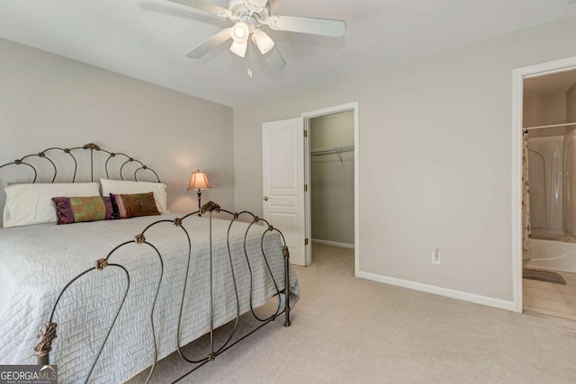 bedroom featuring baseboards, connected bathroom, light colored carpet, ceiling fan, and a spacious closet