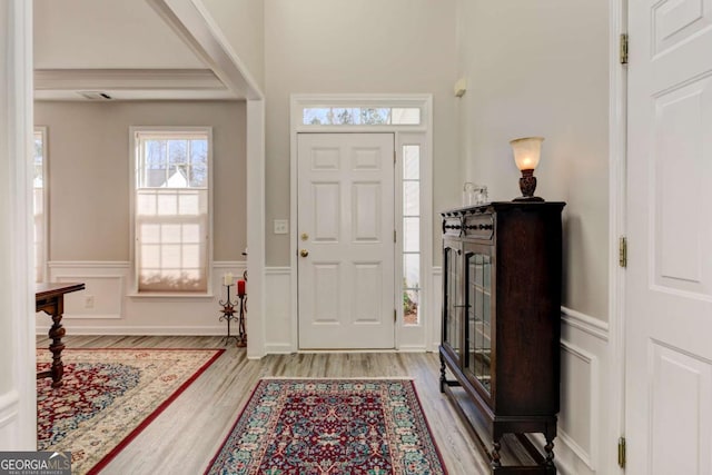 foyer entrance with a wainscoted wall, light wood-type flooring, and a decorative wall