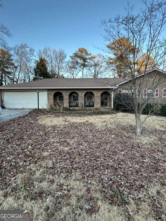 single story home with an attached garage, a shingled roof, and brick siding