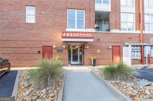 property entrance featuring a standing seam roof, brick siding, metal roof, and a balcony