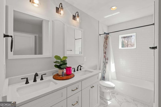 full bath featuring toilet, marble finish floor, double vanity, and a sink