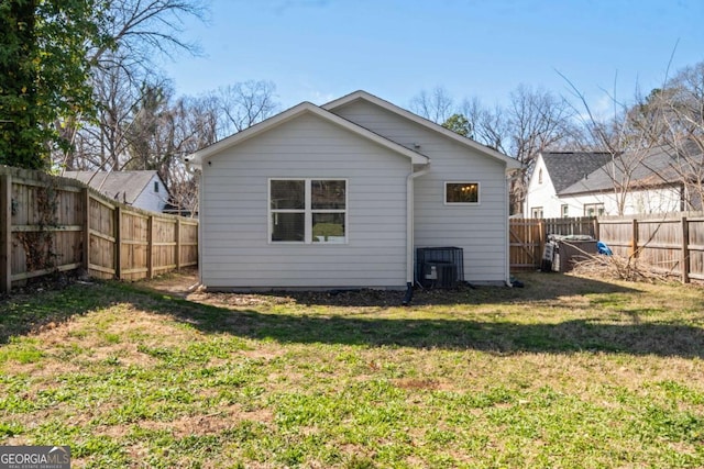 rear view of house featuring a fenced backyard, a lawn, and central air condition unit