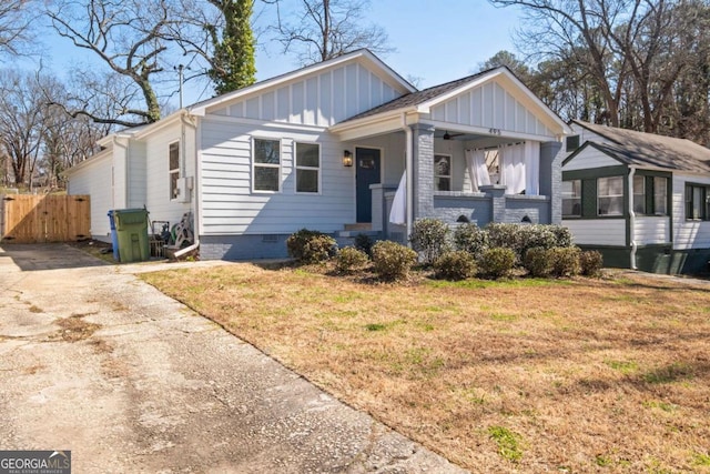 view of front of house with a porch, fence, crawl space, a front lawn, and board and batten siding