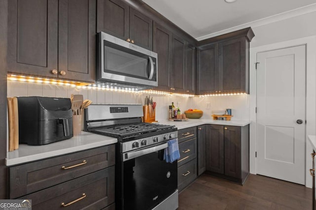 kitchen with stainless steel appliances, dark wood finished floors, backsplash, and light countertops