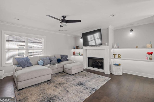 living area featuring dark wood finished floors, a fireplace, crown molding, a ceiling fan, and baseboards