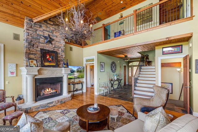 living room featuring a fireplace, visible vents, wood ceiling, wood finished floors, and stairs