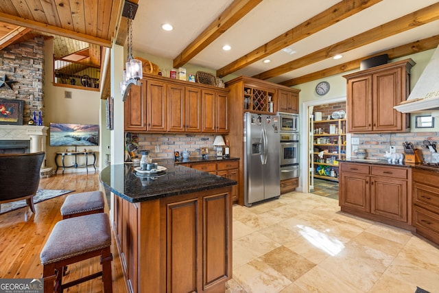 kitchen featuring stainless steel appliances, a warm lit fireplace, brown cabinets, and tasteful backsplash