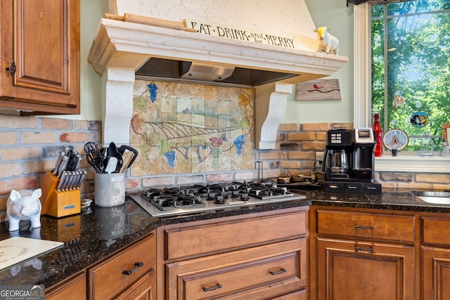 kitchen with a wealth of natural light, brown cabinets, stainless steel gas cooktop, and under cabinet range hood