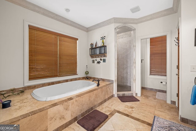 bathroom with a garden tub, ornamental molding, a shower stall, and baseboards